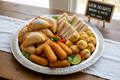 Create a snack tray with empanada, croquettes, sandwichitos and bolita de queso 